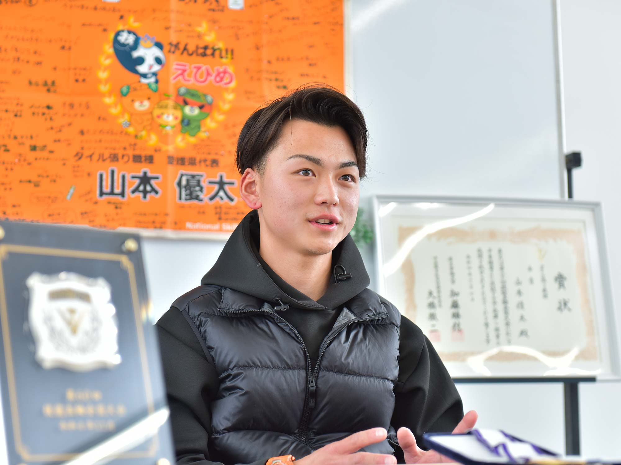 山本さん後ろの横断幕には、多くの人から寄せられた応援メッセージが書かれている。